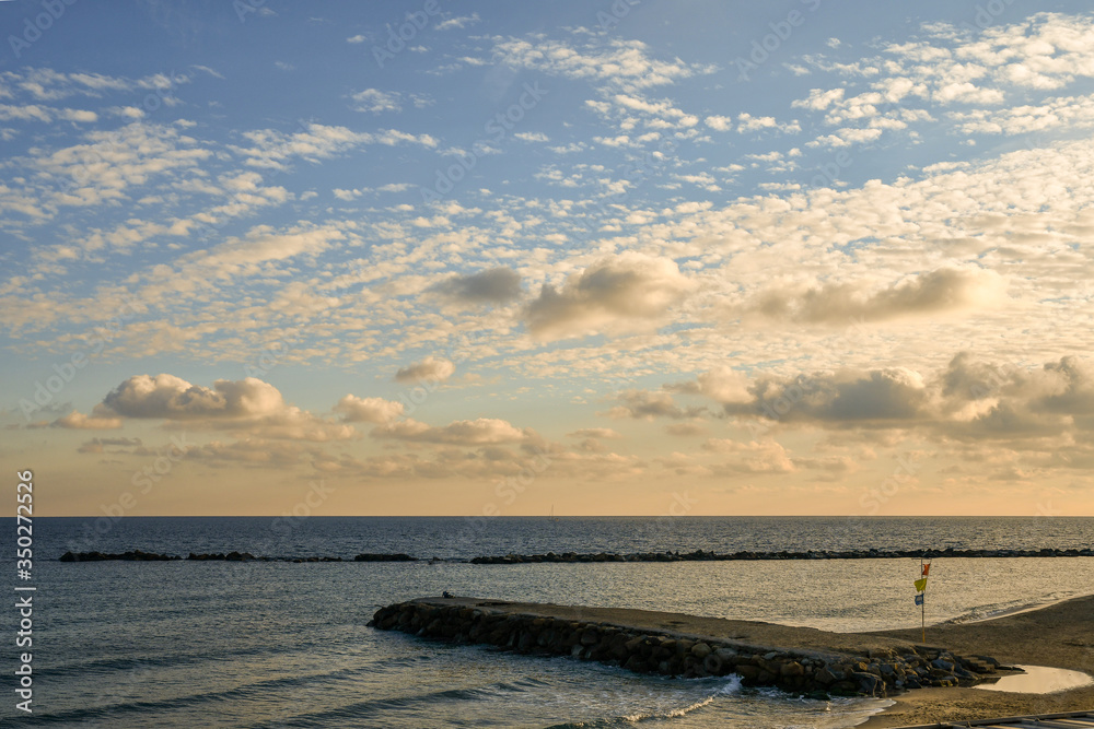 Elevated view of an empty beach with rocky breakwaters and dramatic sky at sunset, Sanremo, Imperia, Liguria, Italy