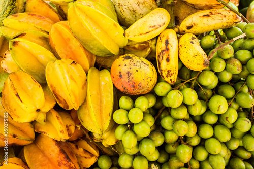 Multi-colored fresh tropical fruits close-up. Carambola, mango, bananas, Spanish Lime. Sweet Caribbean Nature Gifts