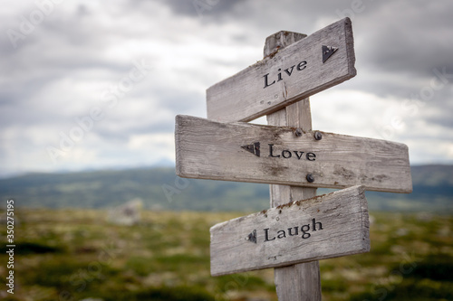live love laugh text engraved on wooden signpost outdoors in nature.