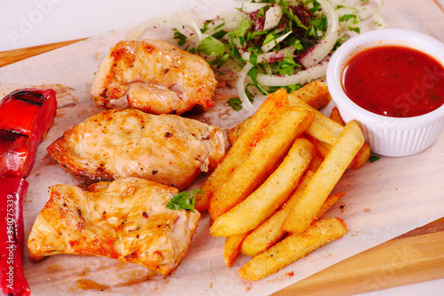Grilled chicken fillet, chili, tomato French fries ketchup onion on wooden Board