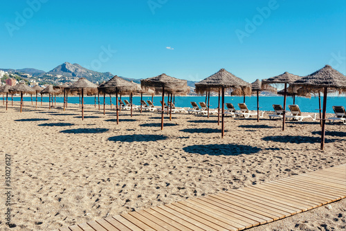 Empty beach with many umbrellas for shadows. Sunny day without people, blue sky over the sea coast © radiokafka