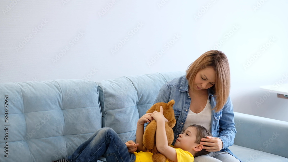 View of mother having fun with baby. mother and son playing with toy on sofa. have fun together. mom is trying to make contact with her hyperactive son View of mother having fun with baby. mother and son playing with toy on sofa. have fun together. mom is trying to make contact with her hyperactive son