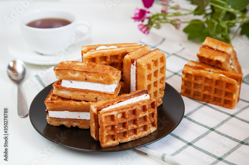 Belgian waffles and tea in a mug on the table.