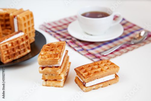 Belgian waffles and tea in a mug on the table.