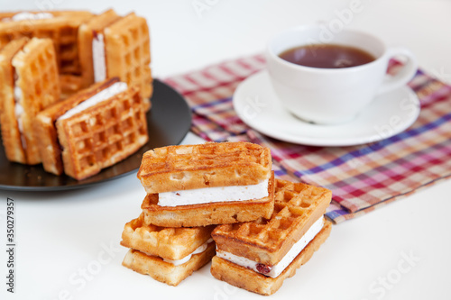 Belgian waffles and tea in a mug on the table.