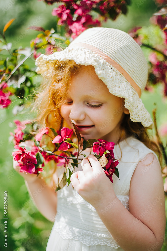 Fototapeta premium portrait of a little red-haired girl in Apple trees