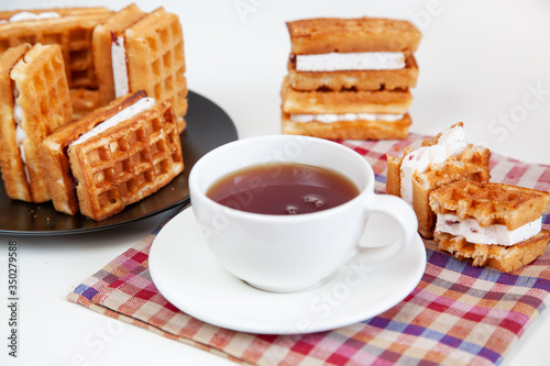 Belgian waffles and tea in a mug on the table.
