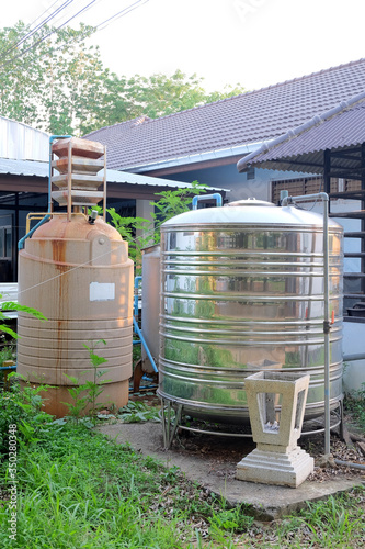 Old fiber water tank and metal water tank at building out door.