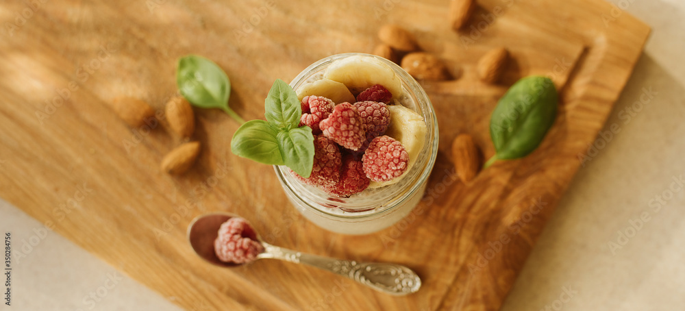 Vegan Chia Pudding with Frozen raspberry, Banana and almond on wooden background. Vegan, morning, breakfast, healthy eating concept. Banner for website. top view Vegan Chia Pudding with Frozen raspberry, Banana and almond on wooden background. Vegan, morning, breakfast, healthy eating concept. Banner for website. top view