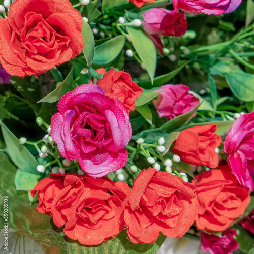 red and violet colored roses on green foliage  artficial flowers bouquet top view close up