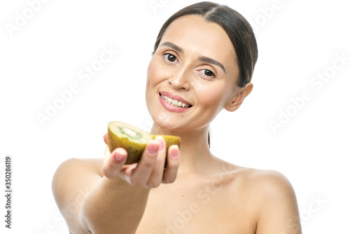 A close-up portrait of a girl with clear skin and a kiwi fruit in her hands