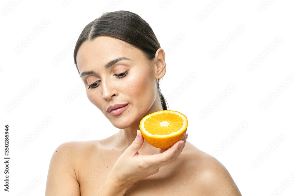 Close up beauty portrait of an excited attractive half naked woman holding orange slices at her face and looking at camera isolated over white background Close up beauty portrait of an excited attractive half naked woman holding orange slices at her face and looking at camera isolated over white background
