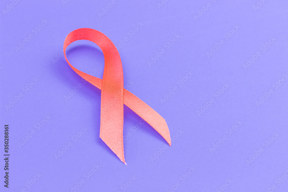 orange ribbon symbolizing International Day of Multiple Sclerosis on a purple background, copy spaсe orange ribbon symbolizing International Day of Multiple Sclerosis on a purple background, copy spaсe