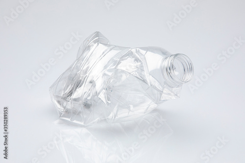 pellucid plastic bottle without cap crushed on itself, isolated in front on white background