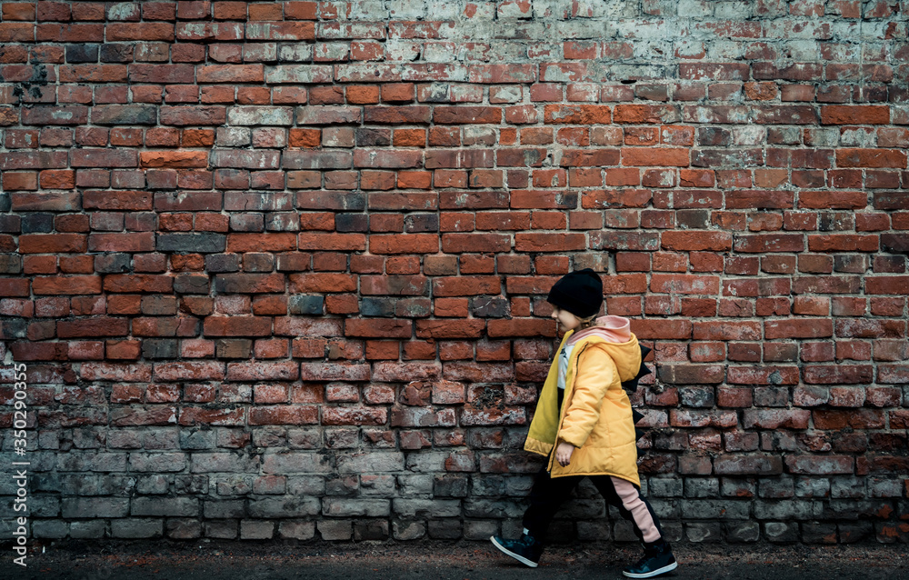 A girl poses against a brick wall. Young model.