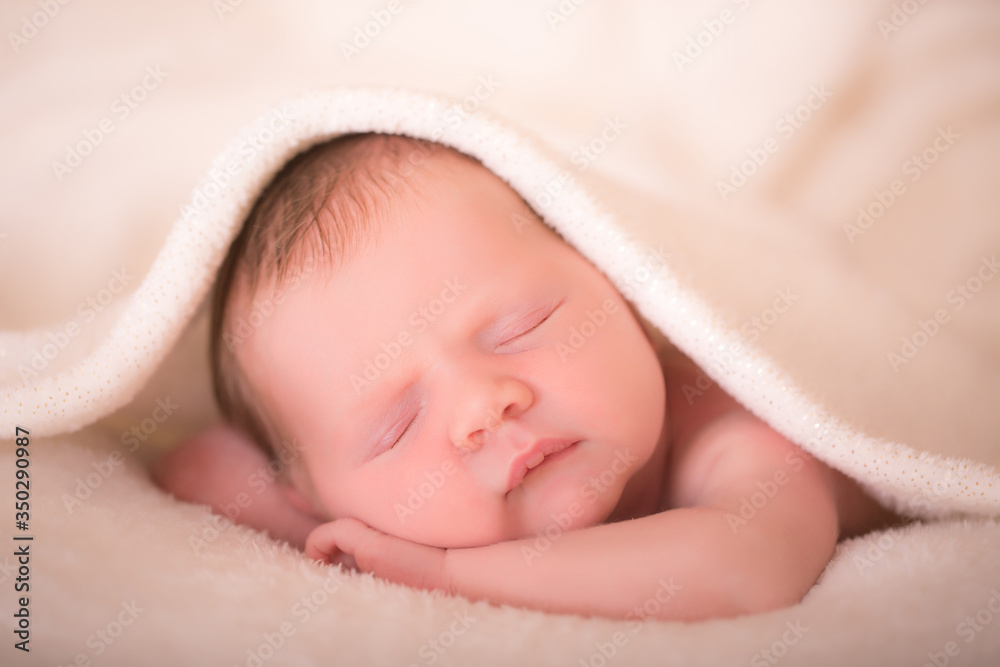 Newborn child relaxing in bed after bath or shower. Nursery for children. Textile and bedding for kids. Little girl sleeping on soft white blanket. Newborn child relaxing in bed after bath or shower. Nursery for children. Textile and bedding for kids. Little girl sleeping on soft white blanket.
