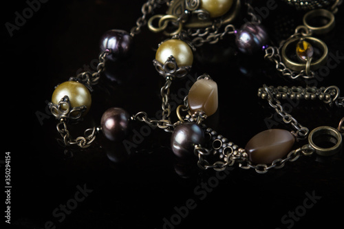Jewelry on black glass. Semi-precious stones with antique chain