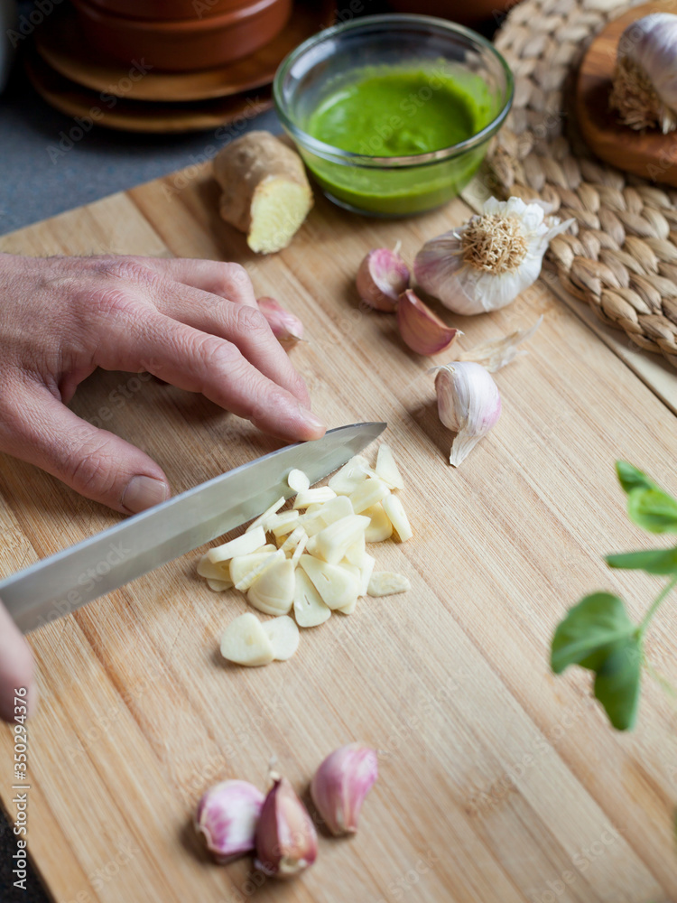 Chopping garlic activity -  male cook is slicing the garlic cloves.