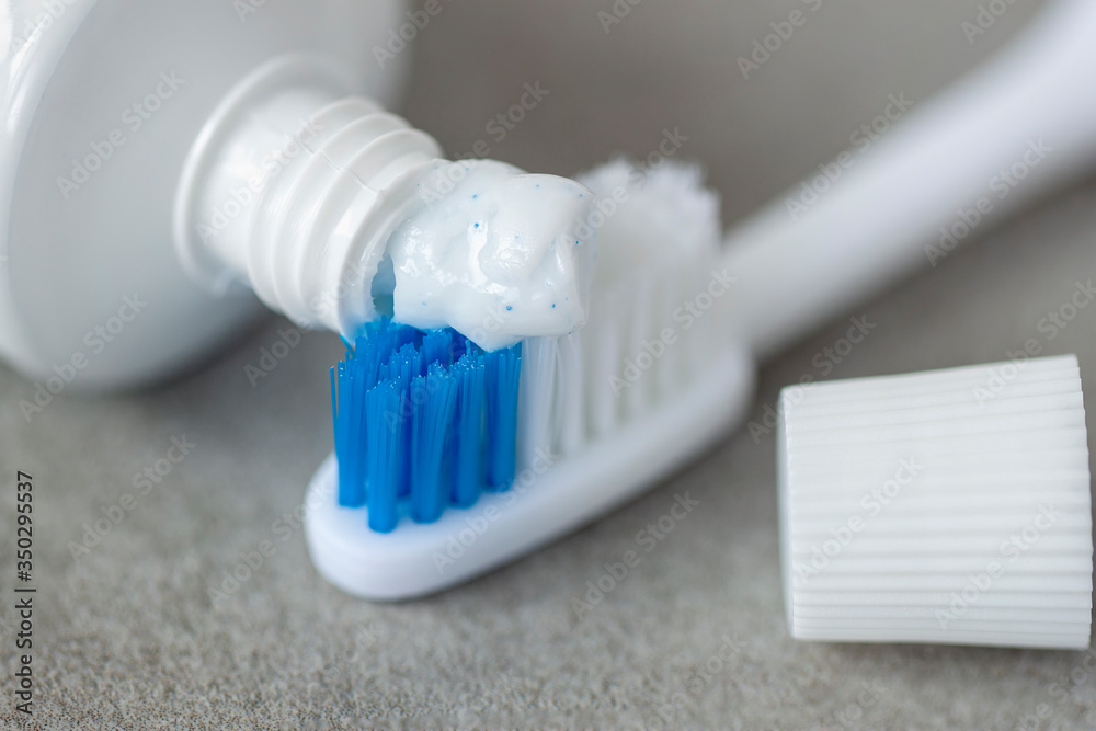 Tube toothpaste squeezes out paste on tooth brush closeup, selective focus, dental care concept Tube toothpaste squeezes out paste on tooth brush closeup, selective focus, dental care concept