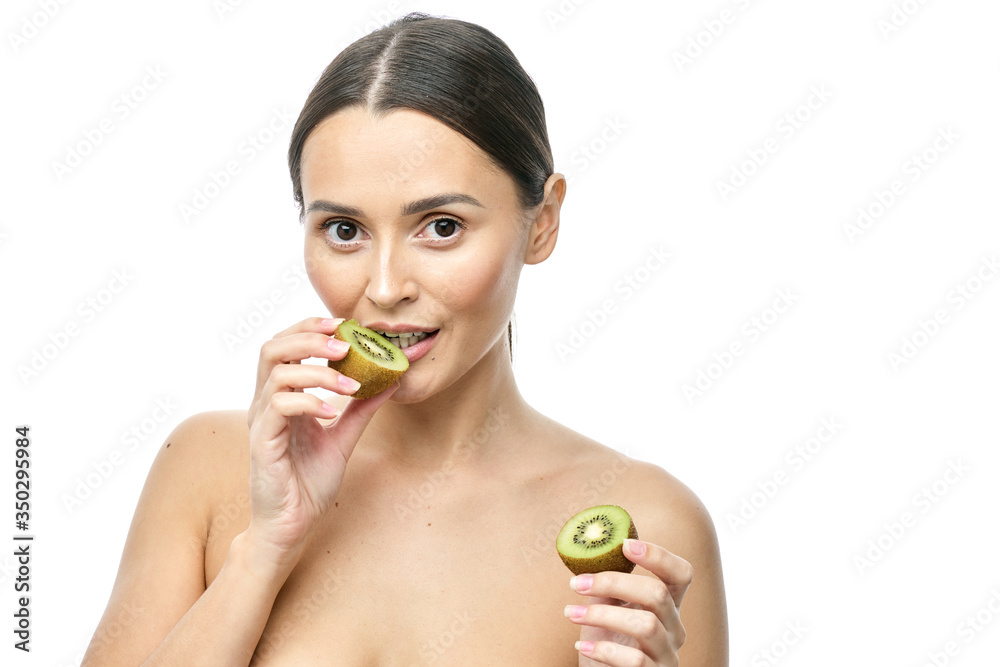 close-up portrait of a girl with clear skin holding a kiwi fruit to her face on a white background close-up portrait of a girl with clear skin holding a kiwi fruit to her face on a white background