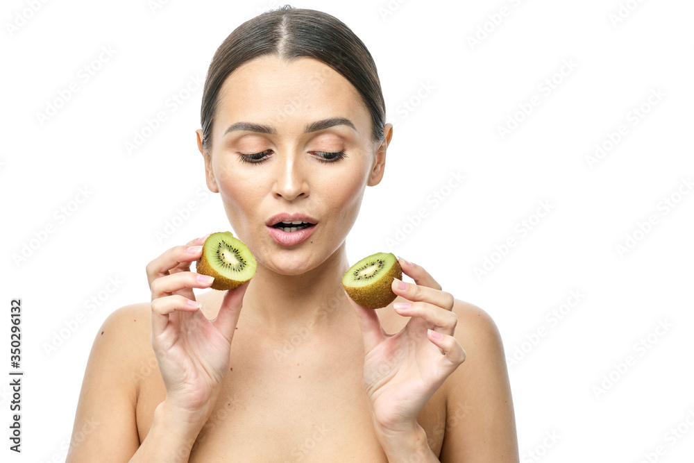 close-up portrait of a girl with clear skin holding a kiwi fruit to her face on a white background close-up portrait of a girl with clear skin holding a kiwi fruit to her face on a white background