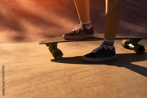 Crop hipster stepping on skateboard