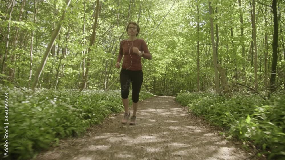 Woman Taking a Run by the Forest Path Towards the Camera Woman Taking a Run by the Forest Path Towards the Camera