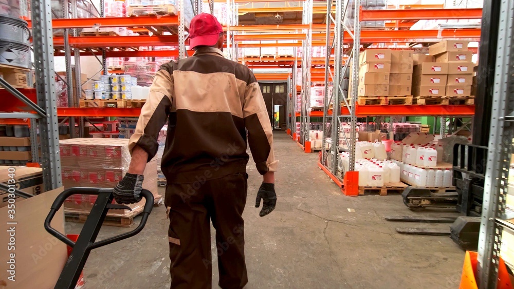 Back of a man in dungarees who is working in a warehouse