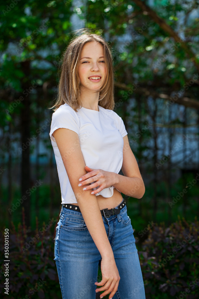 Fototapeta premium Portrait of a young blonde girl in white t-shirt and blue jeans