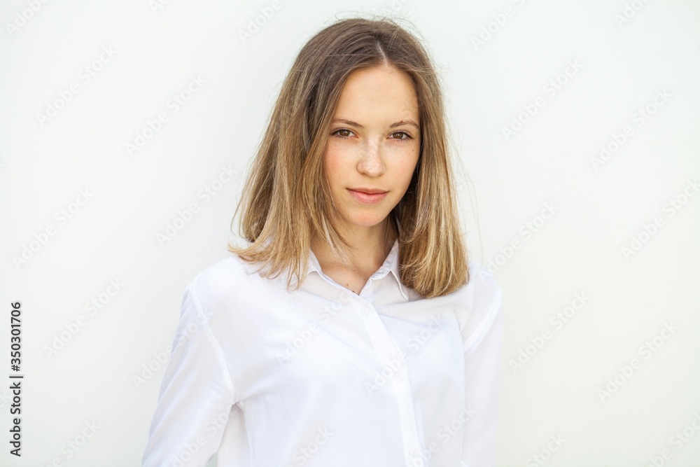 Young blonde girl in white blouse - isolated on white wall background Young blonde girl in white blouse - isolated on white wall background