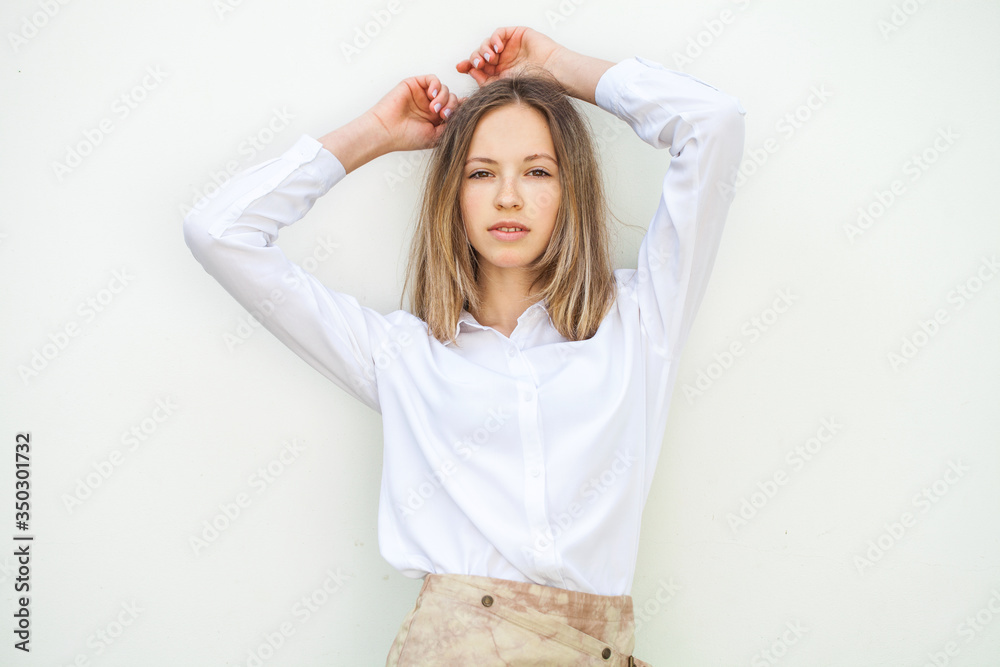 Young blonde girl in white blouse - isolated on white wall background Young blonde girl in white blouse - isolated on white wall background