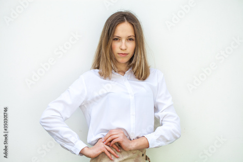 Young blonde girl in white blouse - isolated on white wall background