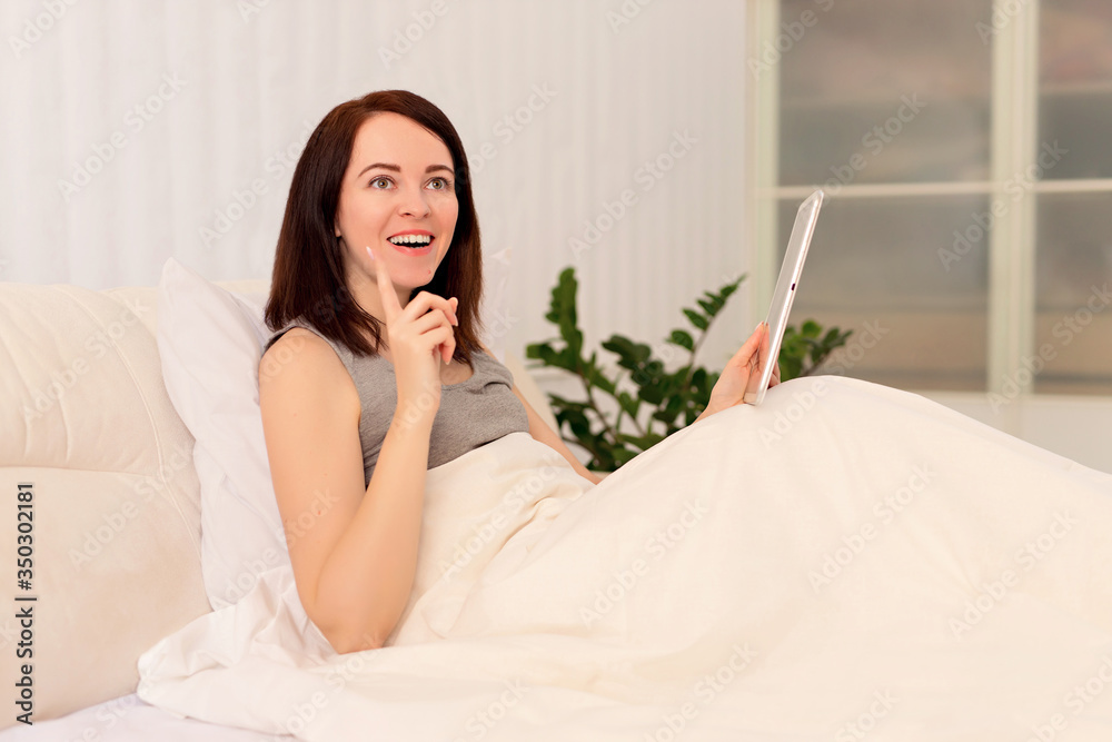 Distance learning online education and work. Happy woman girl working on a tablet. Office work remotely from home on the bed. Distance learning online education and work. Happy woman girl working on a tablet. Office work remotely from home on the bed.