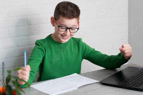 yes fists teenager satisfied with hometasks sitting at table in light room photo