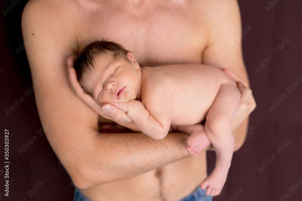 Newborn 5 day naked boy, lies in his father's arms and sleeps. Happy young dad with a naked torso holds a newborn son in his arms. Newborn 5 day naked boy, lies in his father's arms and sleeps. Happy young dad with a naked torso holds a newborn son in his arms.