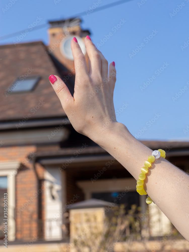 Beautiful female hand with a bracelet on a street background.
