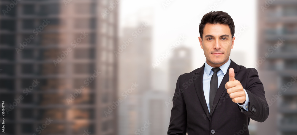 Portrait of a charming businessman dressed in suit thumbs up and looking at camera Portrait of a charming businessman dressed in suit thumbs up and looking at camera