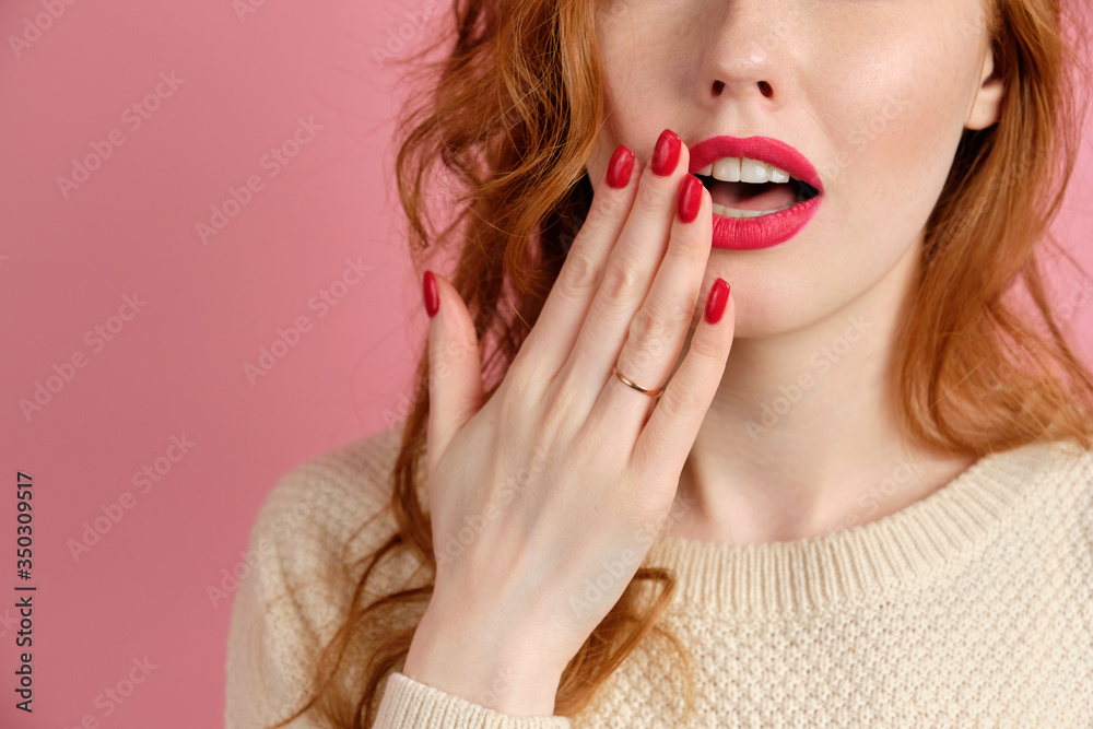 Red girl with red lipstick covers her mouth with a hand with a red manicure, close frame of lips. Red girl with red lipstick covers her mouth with a hand with a red manicure, close frame of lips.