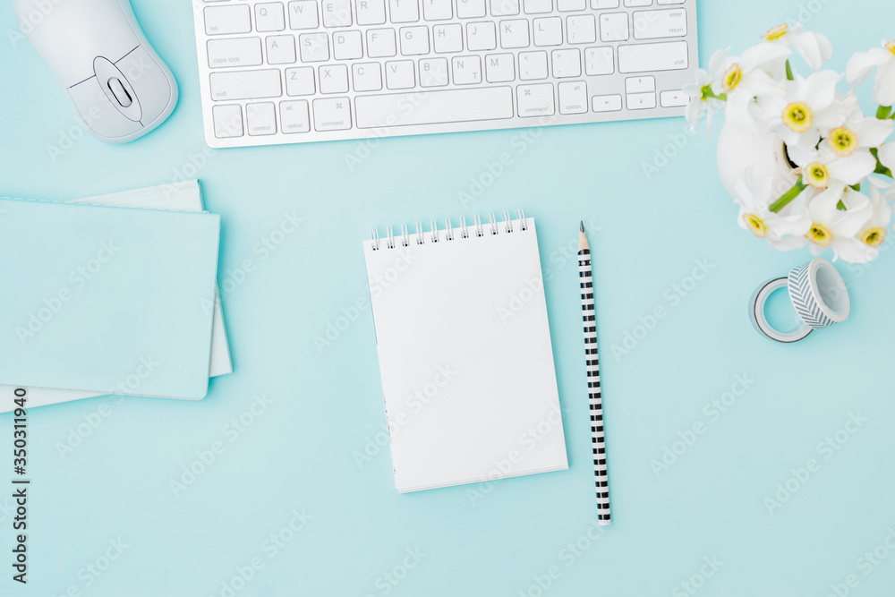 Flat lay blogger or freelancer workspace with a keyboard, notebook, flowers in a vase, office supplies on a color background Flat lay blogger or freelancer workspace with a keyboard, notebook, flowers in a vase, office supplies on a color background