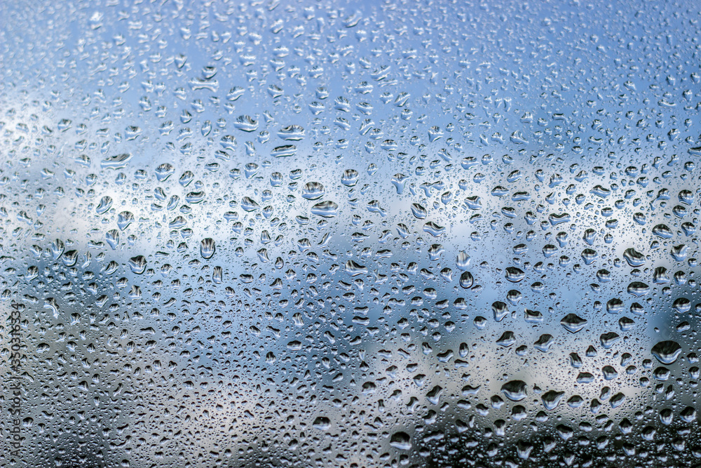 Rain drops on window glass on blue color..