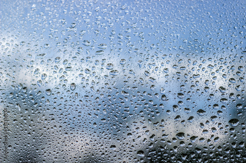 Rain drops on window glass on blue color..