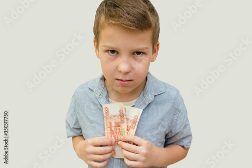 a schoolboy a boy of 10 years of Asian appearance holding in his hands banknotes of 5 thousand Russian rubles on an isolated background finance theme