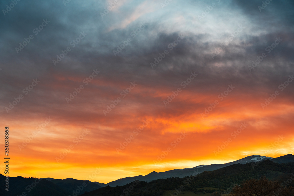 Beautiful bright sunset sky over the mountains silhouette . Dramatic colorful clouds after sunset. Nature backgrounds.