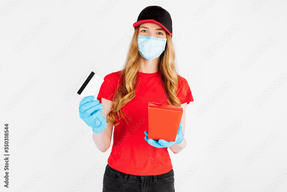 courier, wearing rubber gloves and a medical mask, holds a paper box of food and a credit card for non-cash payment on a white background courier, wearing rubber gloves and a medical mask, holds a paper box of food and a credit card for non-cash payment on a white background