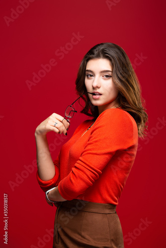 Young girl student or business woman girl with skeptic expression took off glasses on a red background.