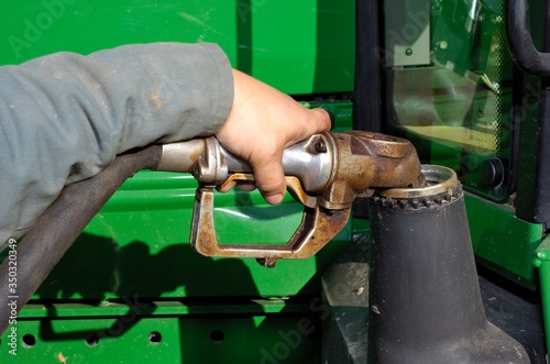 Agriculteur effectuant le plein de gas-oil GNR pour son tracteur. Main tenant le pistolet