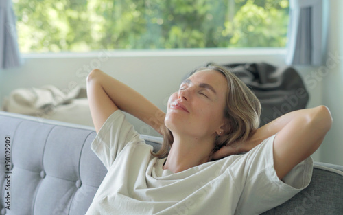 Happy smiling girl lying on sofa enjoying fresh clear air at home