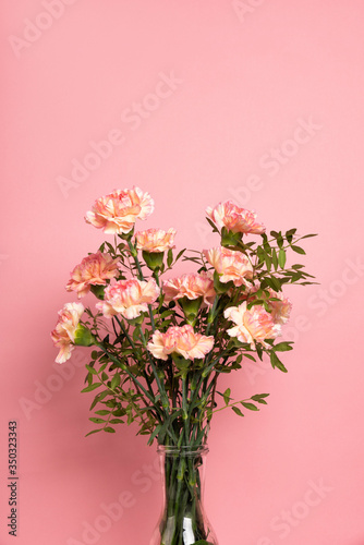Bunch with a beautiful pink carnation flower on white table. Pastel rose background, copy space for your text