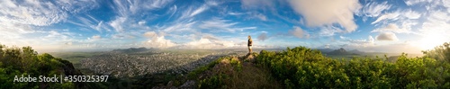 The climber is standing on top of a high mountain in the background of a stunning landscape and sunset. Mauritius Island  panorama