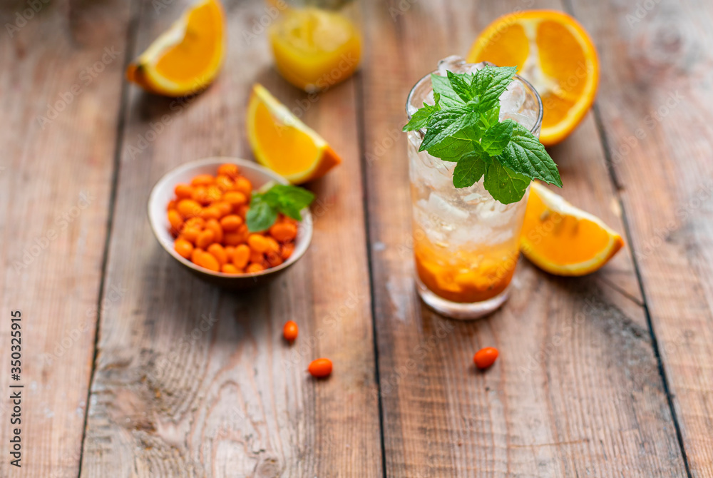 Sea buckthorn ice lemonade with oranges. Fruits and berries outdoors on a wooden table. Detox drinks. Sea buckthorn ice lemonade with oranges. Fruits and berries outdoors on a wooden table. Detox drinks.